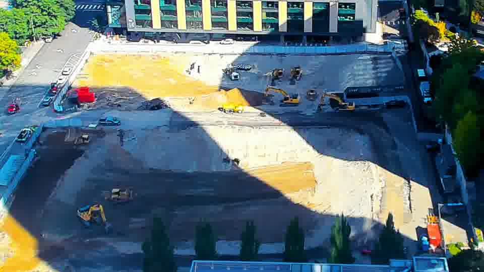 Construction camera frame at 11:00 AM PT. A small, light-colored vehicle has moved from the left side of the site towards the center.