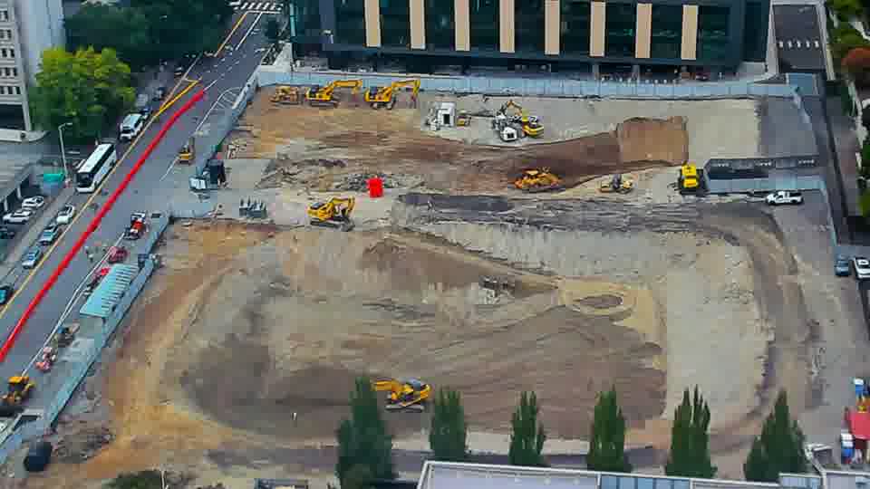 Construction camera frame at 9:00 AM PT. A small orange vehicle has moved slightly within the central area of the block.