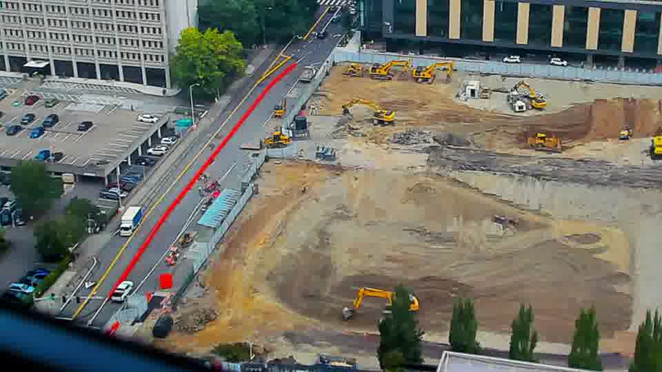 Construction camera frame at 9:45 AM PT. A vehicle has entered the site from the driveway on the left side of the frame.