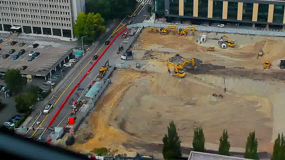 Construction camera frame at 1:30 PM PT. A small white vehicle has moved from the driveway on the left, further down the street. Otherwise, no visible change between these frames.