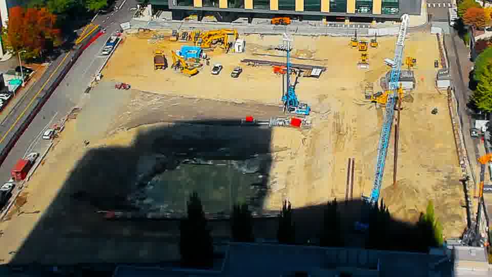 Construction camera frame at 1:00 PM PT. A shadow now covers the central cut in the site.