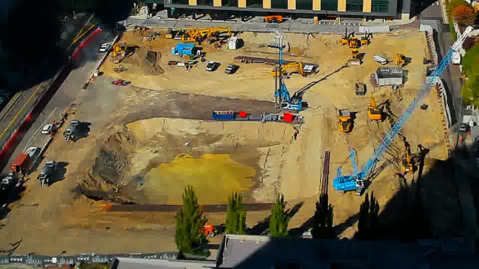 Construction camera frame at 2:45 PM PT. A small red container has appeared near the center of the site, within the large cut.